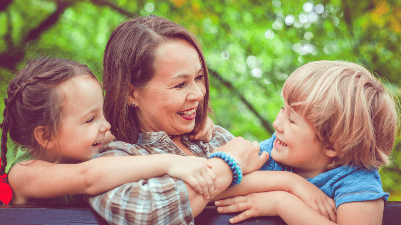 Nainen, tyttö ja poika kesäisessä metsässä.